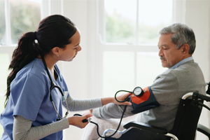 A healthcare practitioner checking a patient's blood pressure using a cuff and monitor